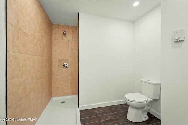 bathroom with a tile shower and toilet