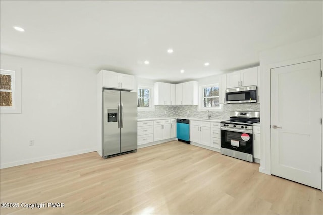 kitchen with sink, white cabinetry, stainless steel appliances, light hardwood / wood-style floors, and decorative backsplash