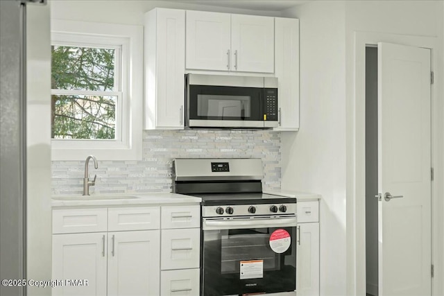 kitchen with stainless steel appliances, sink, white cabinets, and backsplash