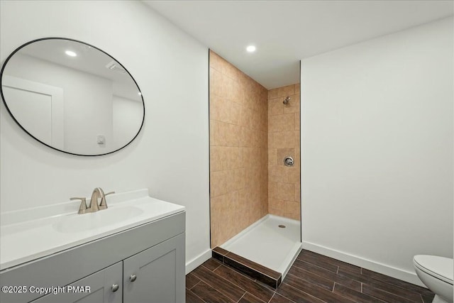 bathroom with vanity, a tile shower, and toilet