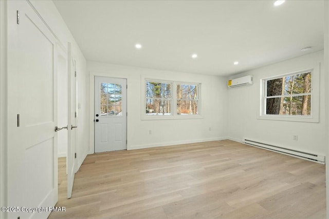 interior space featuring a baseboard radiator, a wall mounted air conditioner, and light hardwood / wood-style flooring