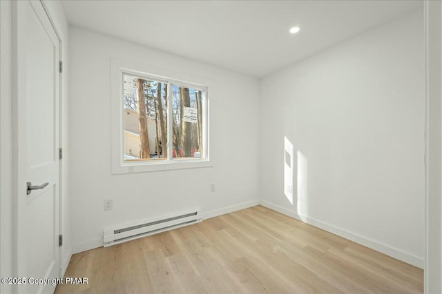 unfurnished room with light wood-type flooring and a baseboard heating unit