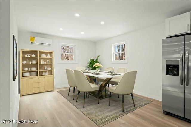 dining space featuring light wood-type flooring and an AC wall unit