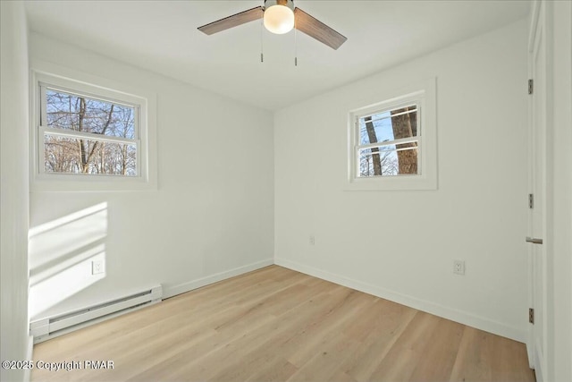 empty room featuring light hardwood / wood-style flooring, a wealth of natural light, ceiling fan, and baseboard heating