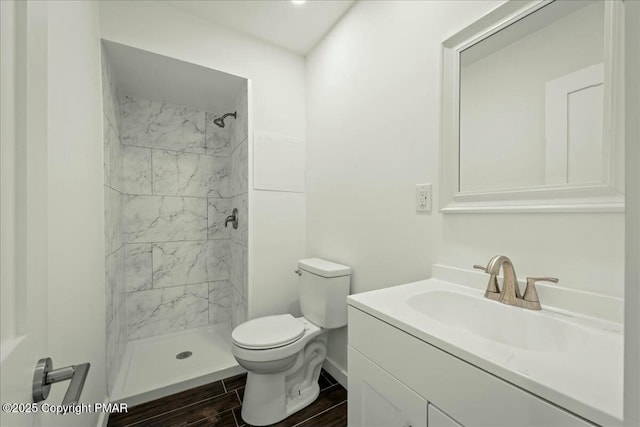 bathroom with tiled shower, vanity, and toilet