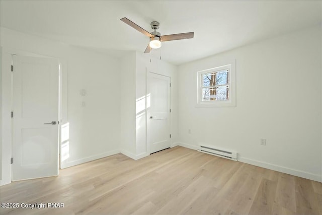 spare room featuring a baseboard heating unit, light hardwood / wood-style floors, and ceiling fan