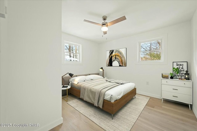 bedroom with multiple windows, ceiling fan, and light hardwood / wood-style floors