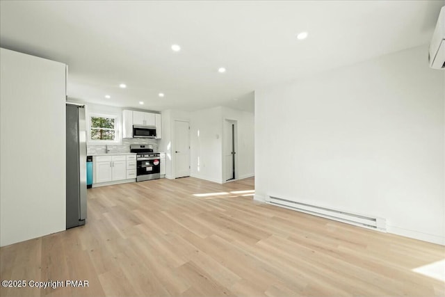 unfurnished living room featuring baseboard heating, light hardwood / wood-style flooring, and an AC wall unit