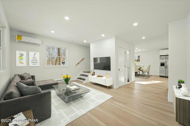 living room featuring a wall mounted AC and light hardwood / wood-style flooring