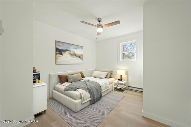 bedroom with ceiling fan, light hardwood / wood-style flooring, and a baseboard radiator