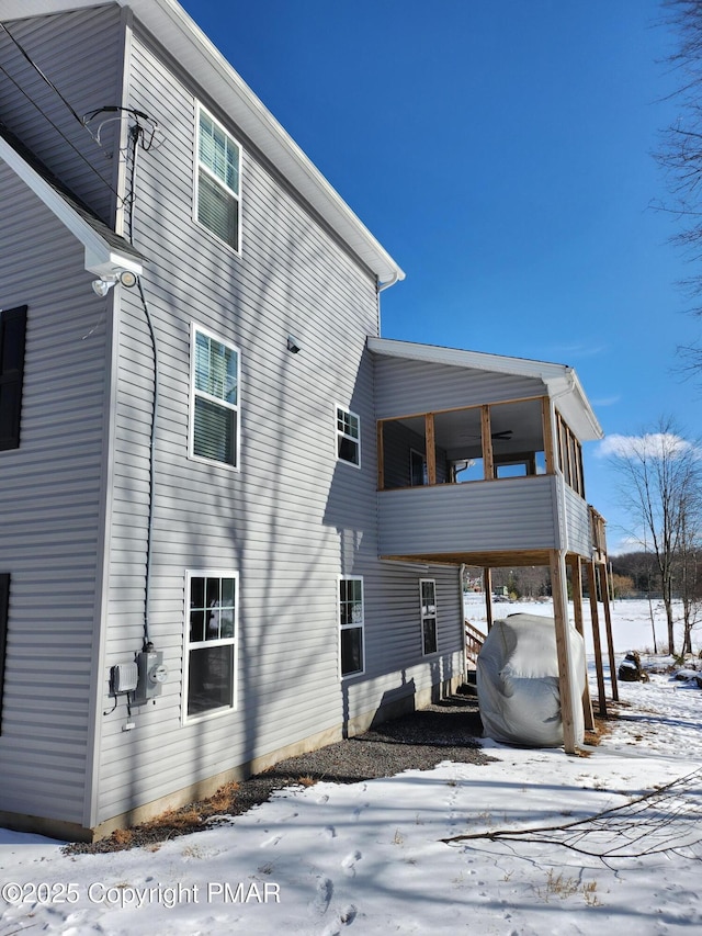 snow covered rear of property with a balcony