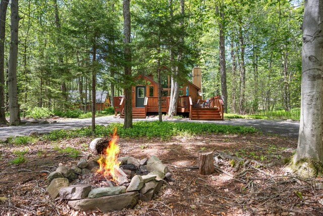 2107 Oak Rd, Pocono Pines, PA 18350 - view of front of home featuring an outdoor fire pit, a deck, a wooded view, and a chimney