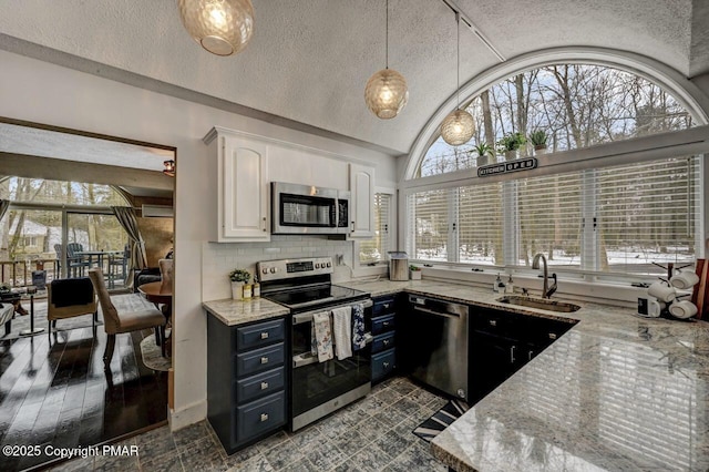 kitchen featuring sink, appliances with stainless steel finishes, pendant lighting, light stone countertops, and white cabinets