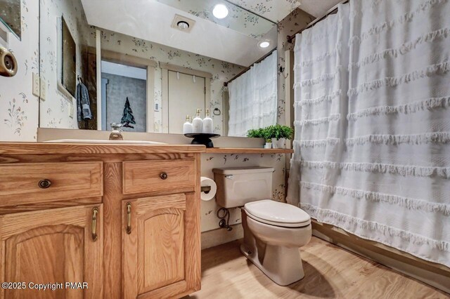 bathroom with hardwood / wood-style flooring, vanity, toilet, and curtained shower