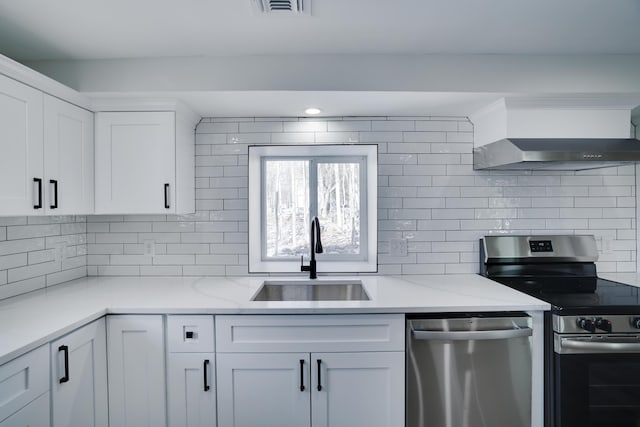 kitchen with tasteful backsplash, white cabinets, stainless steel appliances, wall chimney exhaust hood, and a sink