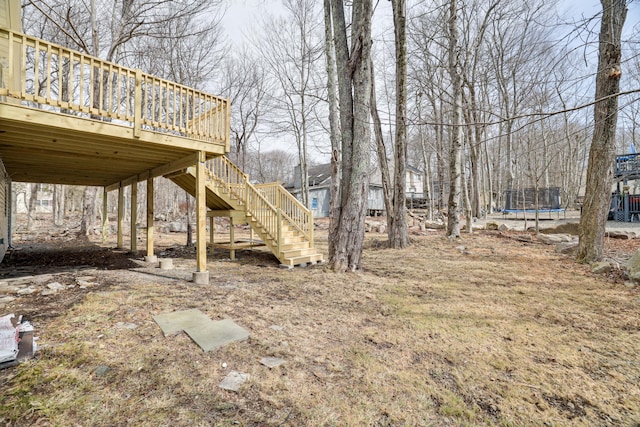 view of yard with stairway, a wooden deck, and a trampoline