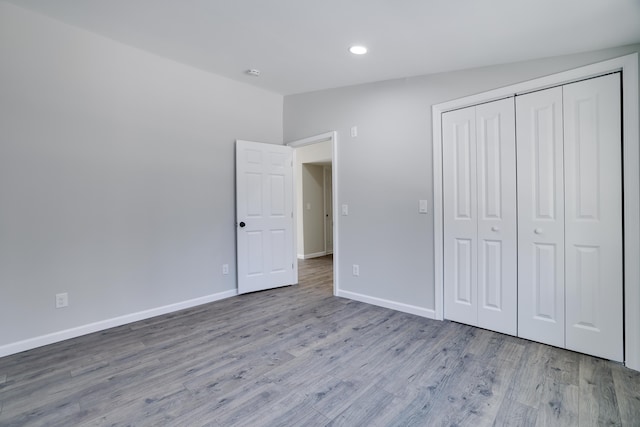 unfurnished bedroom with a closet, baseboards, and wood finished floors