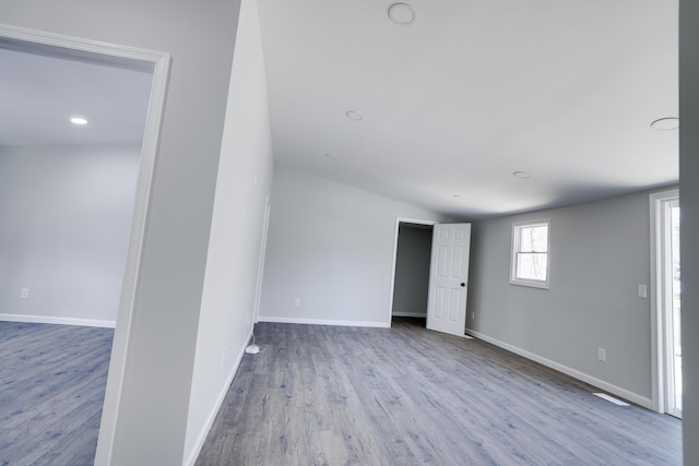 unfurnished room featuring vaulted ceiling, wood finished floors, and baseboards