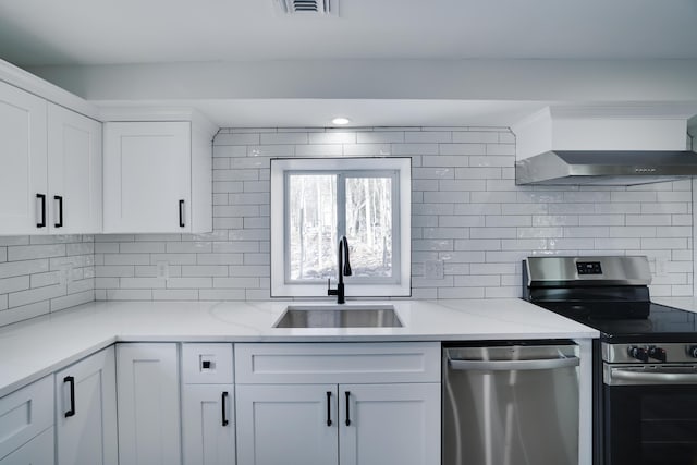 kitchen with a sink, stainless steel appliances, tasteful backsplash, wall chimney exhaust hood, and white cabinets