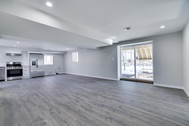 unfurnished living room with dark wood-type flooring, recessed lighting, baseboards, and visible vents