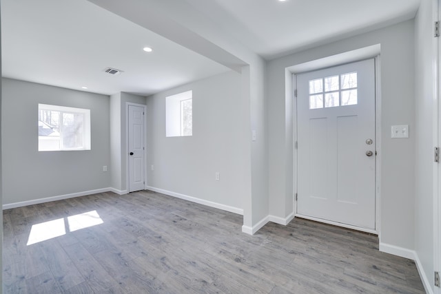 entrance foyer with wood finished floors, visible vents, a wealth of natural light, and baseboards