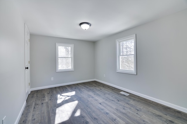 empty room with dark wood finished floors, visible vents, and plenty of natural light