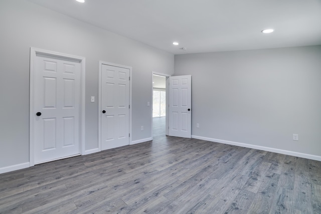 unfurnished bedroom featuring recessed lighting, wood finished floors, and baseboards