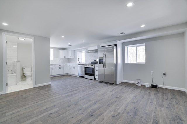 kitchen with visible vents, wood finished floors, white cabinetry, appliances with stainless steel finishes, and decorative backsplash