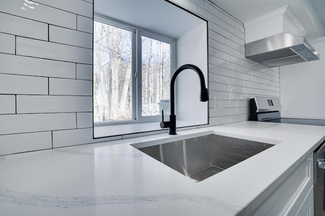 interior details with extractor fan, stainless steel electric range oven, light stone counters, decorative backsplash, and a sink