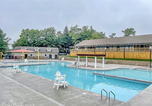 community pool with a patio area and fence