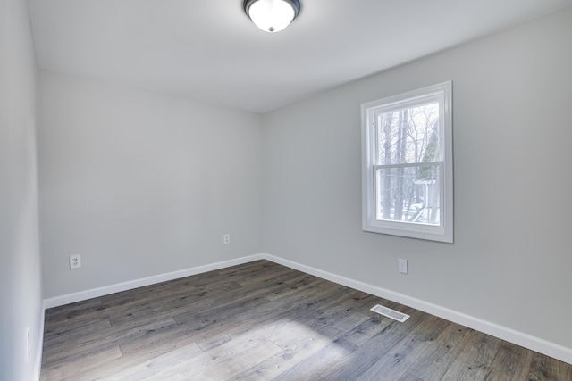 empty room featuring visible vents, baseboards, and wood finished floors