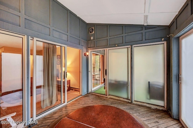 interior space with high vaulted ceiling, wood-type flooring, and a decorative wall