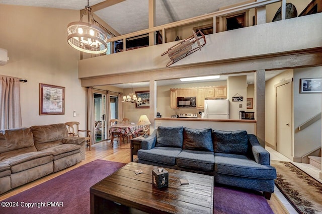 living area featuring a notable chandelier, a high ceiling, light wood-type flooring, a wall mounted air conditioner, and stairs