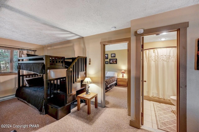 bedroom featuring carpet, ensuite bath, a textured ceiling, and baseboard heating