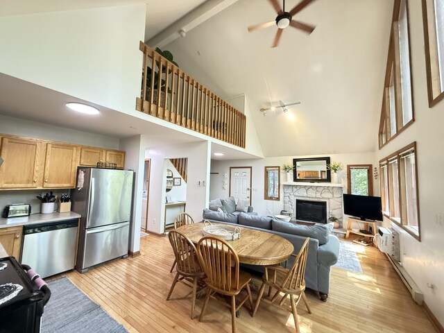 6414 Decker Rd, Bushkill, PA 18324 - dining area with high vaulted ceiling, a ceiling fan, a fireplace, a baseboard heating unit, and light wood-style flooring