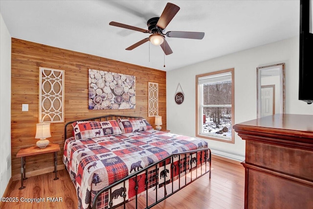 bedroom featuring a ceiling fan, wooden walls, and wood finished floors