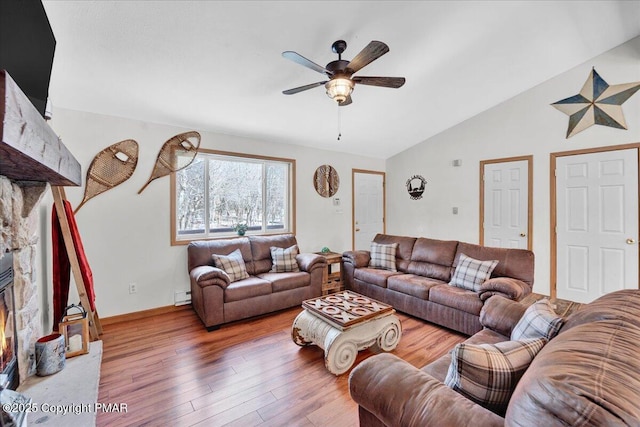 living area featuring a ceiling fan, wood finished floors, lofted ceiling, baseboard heating, and a large fireplace