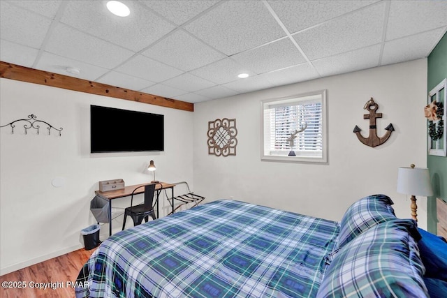 bedroom featuring baseboards, a paneled ceiling, and wood finished floors