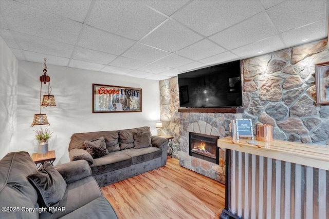 living room with a drop ceiling, a fireplace, and wood finished floors