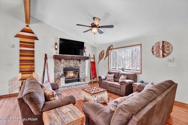 living room with a stone fireplace, vaulted ceiling, a ceiling fan, and light wood-type flooring