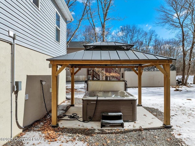 snow covered patio featuring a gazebo and a hot tub