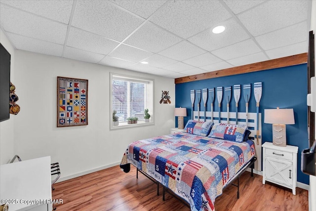 bedroom featuring a paneled ceiling, baseboards, and wood finished floors