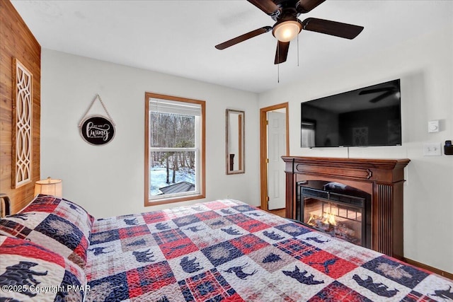 bedroom with a glass covered fireplace and a ceiling fan