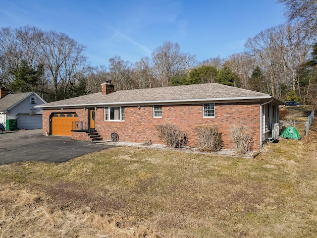 view of home's exterior with brick siding, a chimney, aphalt driveway, and a garage