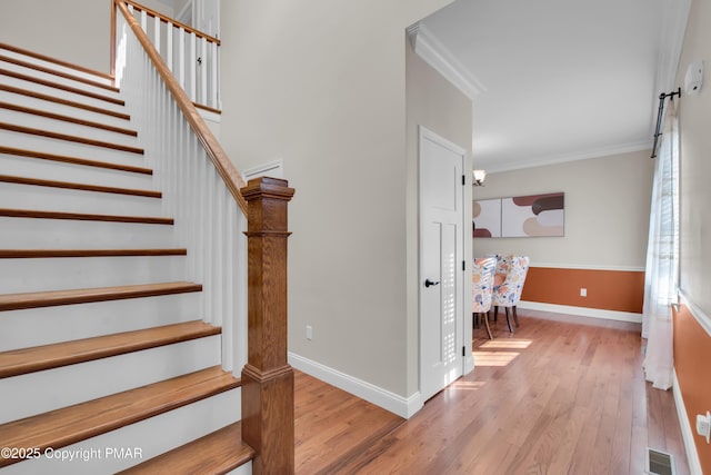 stairway with baseboards, visible vents, crown molding, and wood finished floors