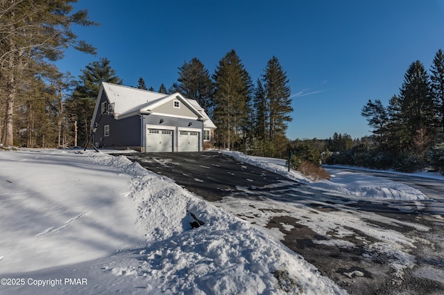 view of snow covered exterior with a garage and aphalt driveway