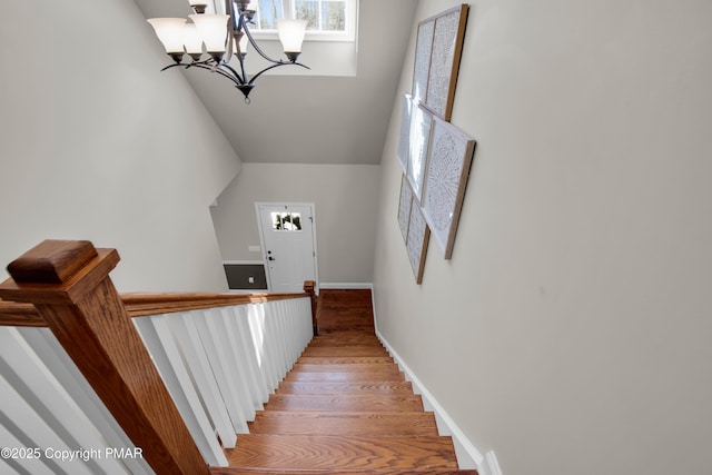 stairs featuring a notable chandelier, wood finished floors, and baseboards