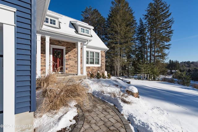 snow covered property entrance with stone siding