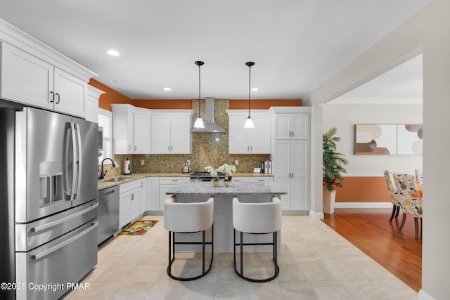 kitchen featuring appliances with stainless steel finishes, white cabinetry, a sink, and wall chimney exhaust hood