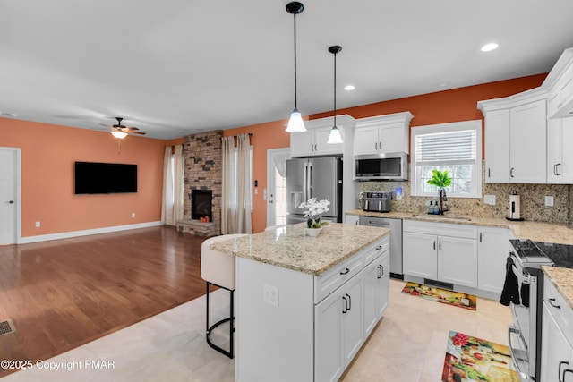 kitchen featuring open floor plan, appliances with stainless steel finishes, a sink, and tasteful backsplash